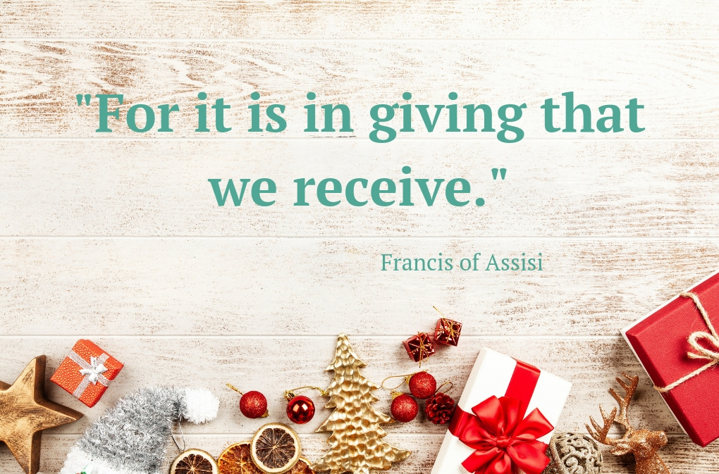 gifts against a white-washed wood background with text that says "For it is in giving that we receive."