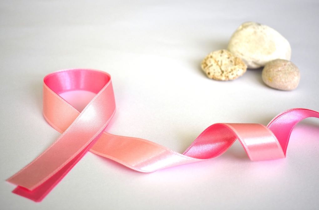 Photo of pink ribbon for breast cancer prevention sitting beside small stones