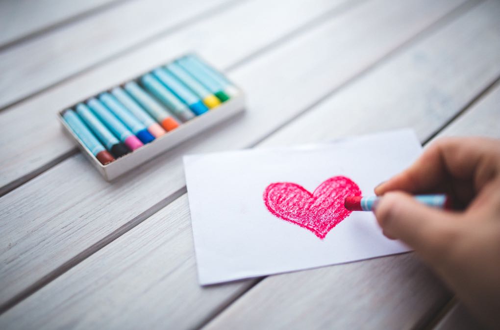 Photo of hand drawing a heart on a card as an example of Valentine's Day on a budget