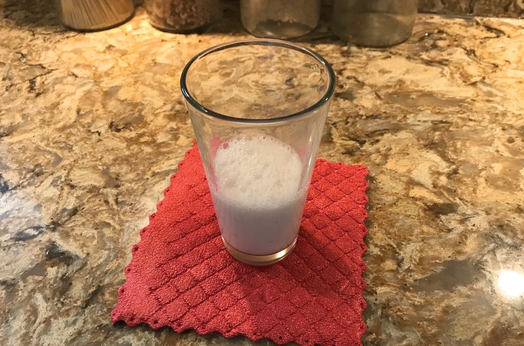 Photo of glass of almond milk sitting on red pad as example of how to weigh the pros and cons of almond milk