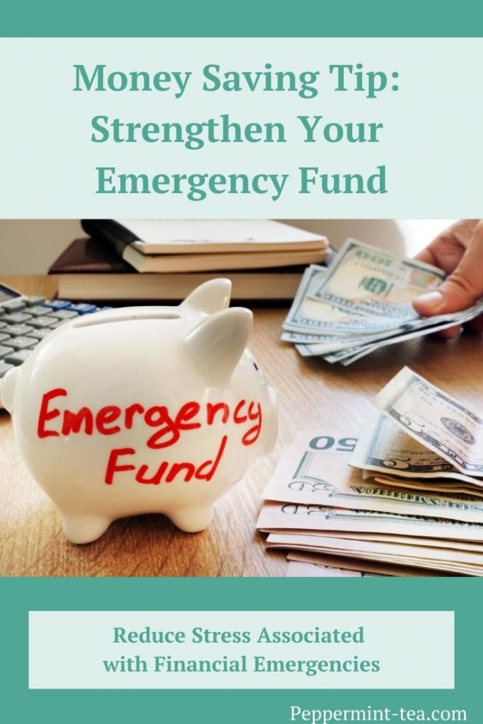 Photo of white piggy bank with emergency fund written on it in red ink beside stacks of money