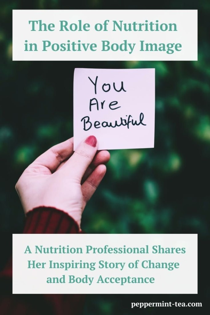 Photo of a woman's hand holding up a sticky note saying "You are beautiful" as an example of positive body image